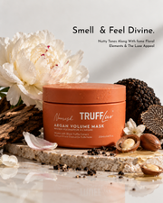 Nourish TRUFFluv Argan Volume Mask in a terracotta-colored jar, styled on a stone slab with argan nuts, a white peony flower, and dark chocolate pieces against a clean white background with promotional text.